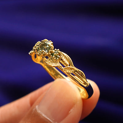 A model holding a Green Sapphire Leaves and Vines Ring tilted to show the inside of the ring