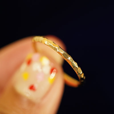 A model holding a Curvy Hammered Band tilted to show the side of the ring