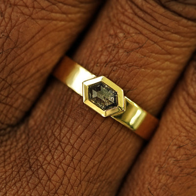 Close up view of a model's hand wearing a solid yellow gold Hexagon Diamond Band