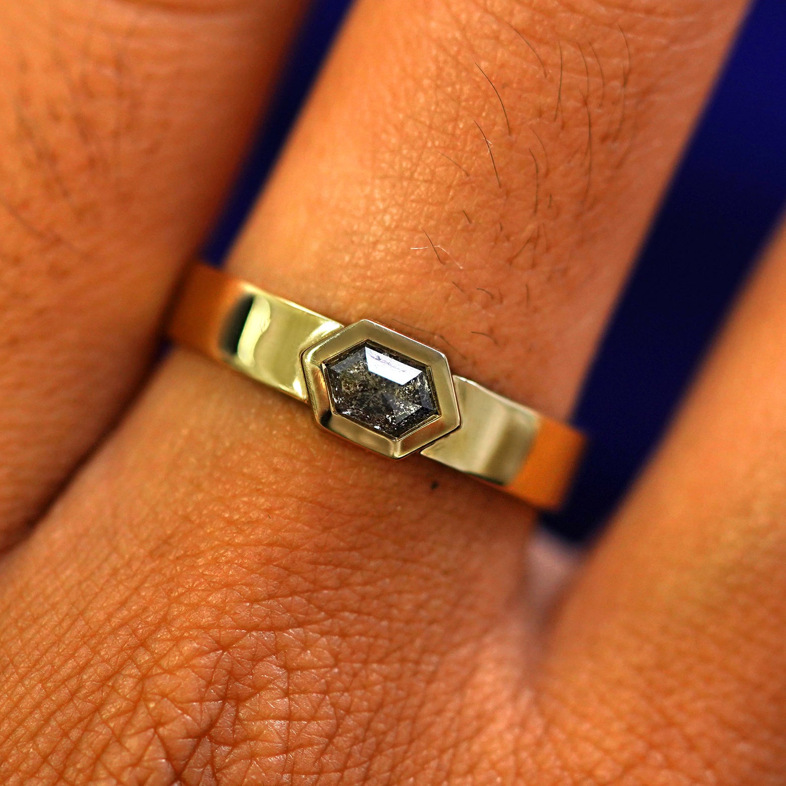 Close up view of a model's fingers wearing a 14k yellow gold Hexagon Diamond Band