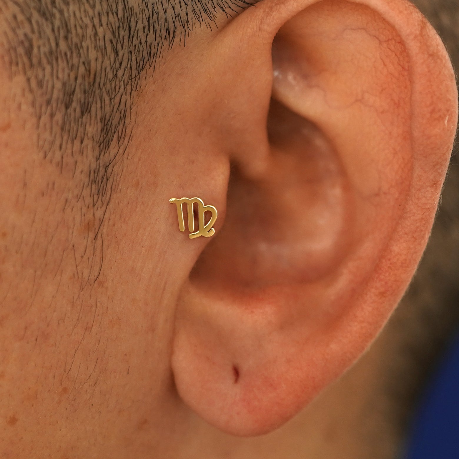 A model's ear wearing a 14k yellow gold Virgo Horoscope Flatback in a tragus piercing