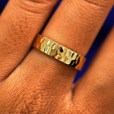 A yellow gold Industrial Hammered Band in a model's hand showing the thickness of the band