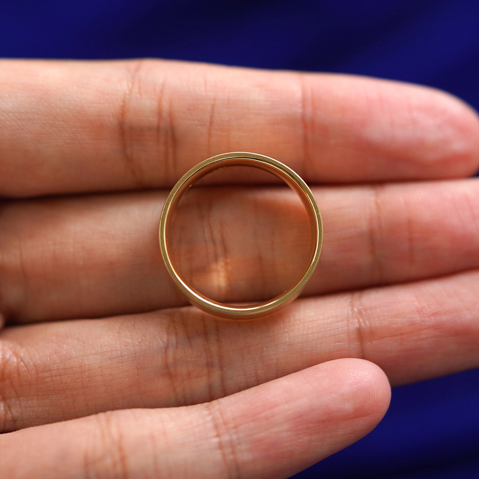 A yellow gold Industrial Matte Band in a model's hand showing the thickness of the band