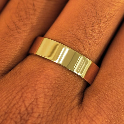 Close up view of a model's fingers wearing a 14k yellow gold Industrial Mirror Band