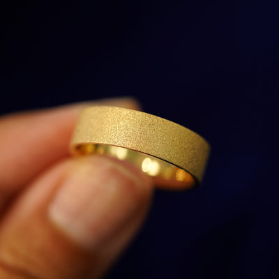A model holding a Industrial Stardust Band tilted to show the details of the star dust finish show the side of the ring