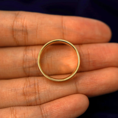 A yellow gold Industrial Stardust Band in a model's hand showing the thickness of the band