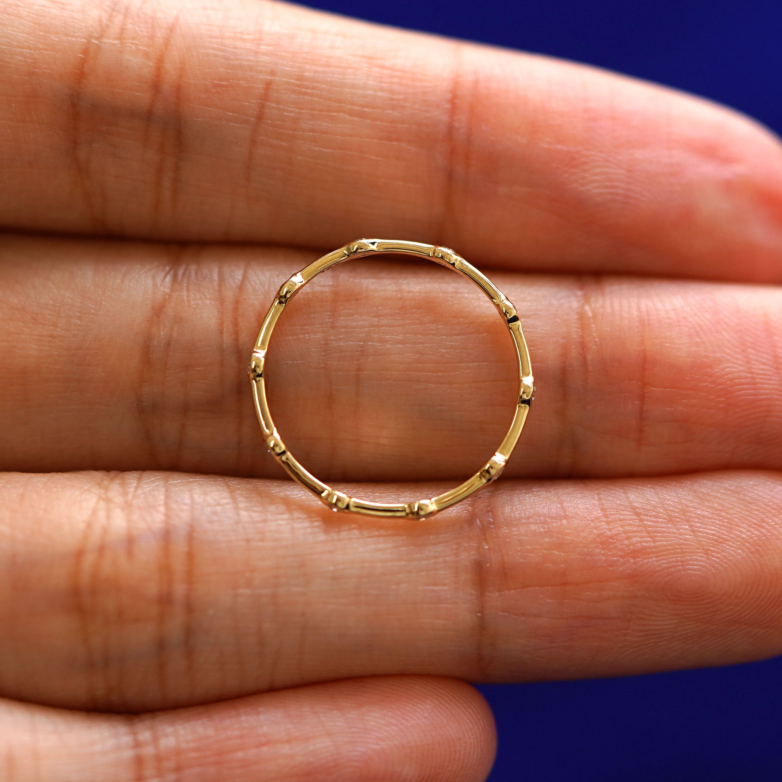 A yellow gold Spaced Infinity Ring in a model's hand showing the thickness of the band