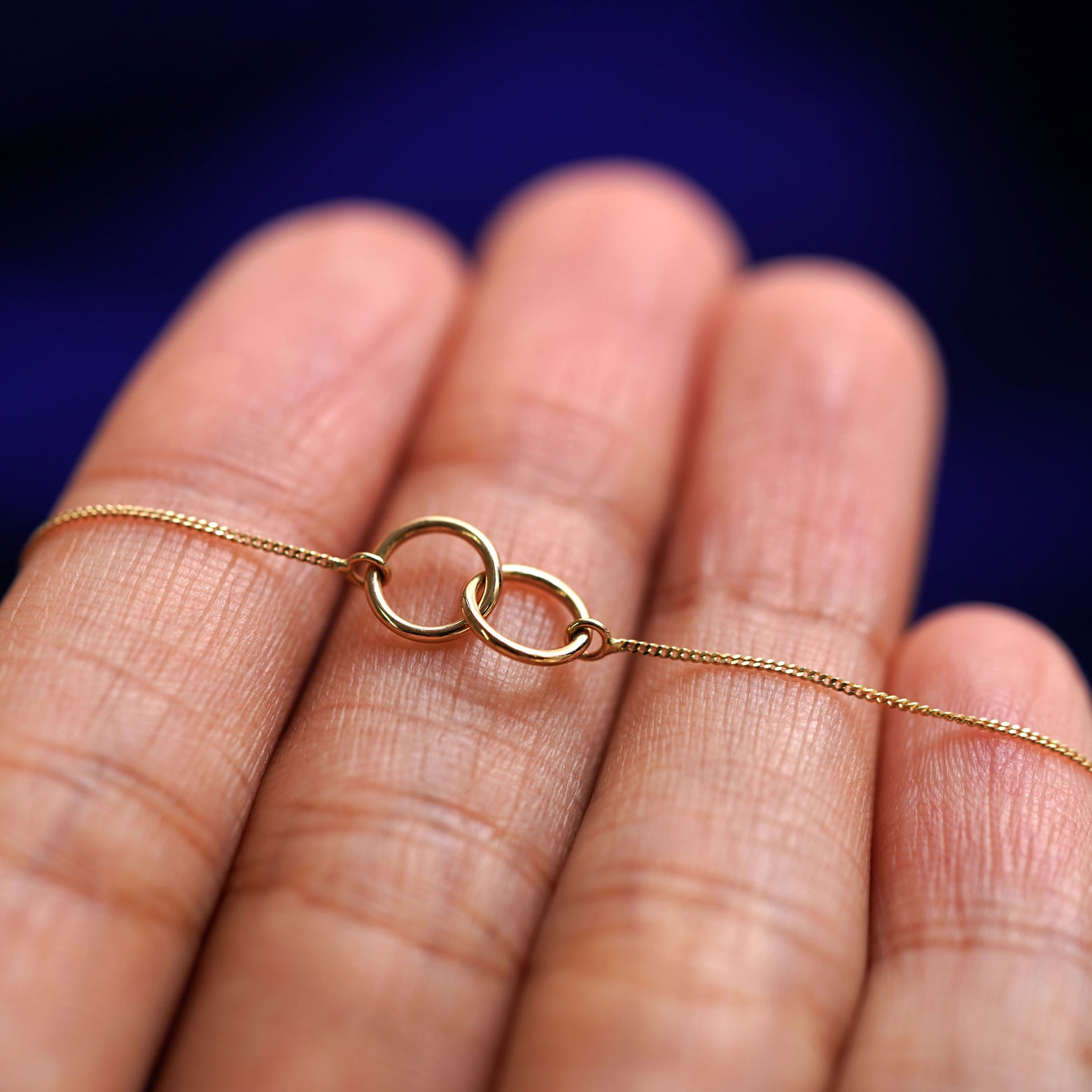 A yellow gold Mini Bound Together Bracelet resting on a model's fingers