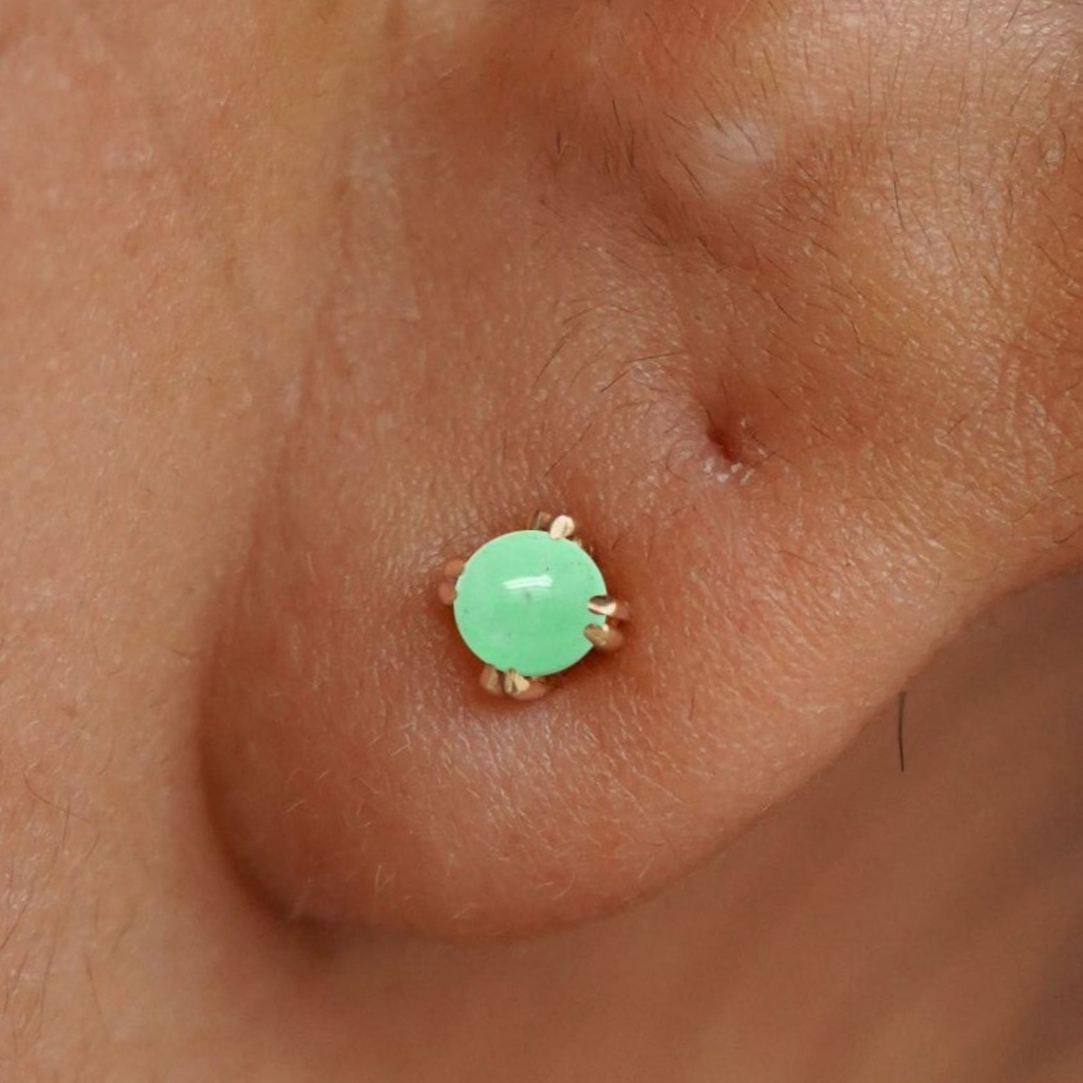 Close up view of a model's ear wearing a 14k yellow gold Green Jade Earring