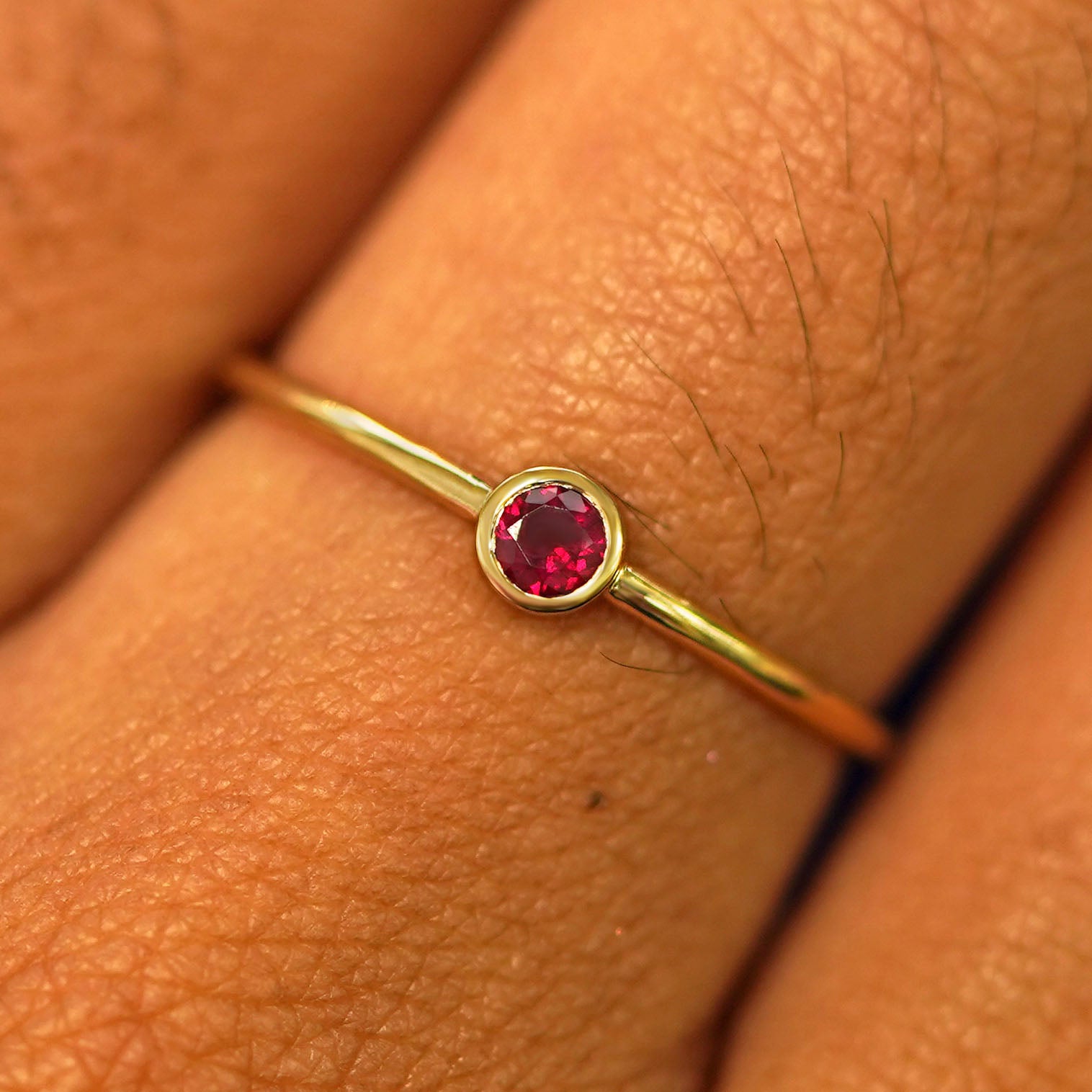 Close up view of a model's fingers wearing a 14k yellow gold Garnet Ring