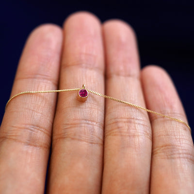 A 14k gold Ruby Necklace draped over a model's fingers