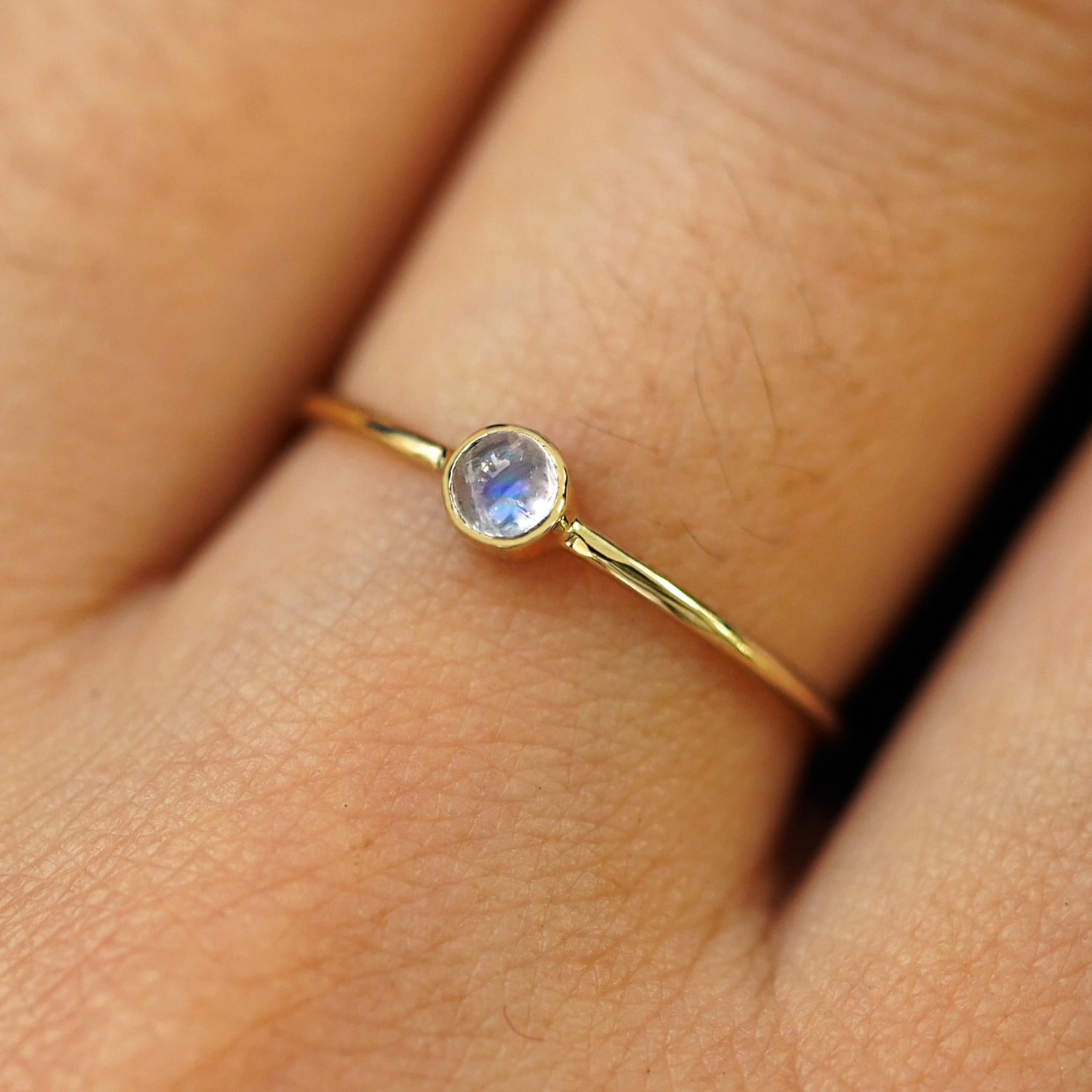 Close up view of a model's fingers wearing a 14k yellow gold Moonstone Ring