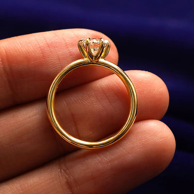 A yellow gold Round Lab Diamond Ring in a model's hand showing the thickness of the band