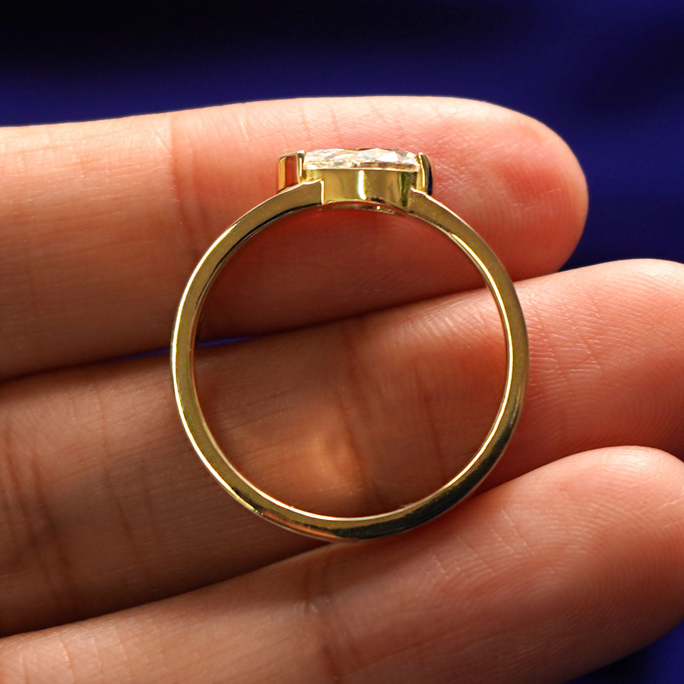 A yellow gold Lab Diamond Pear Ring in a model's hand showing the thickness of the band