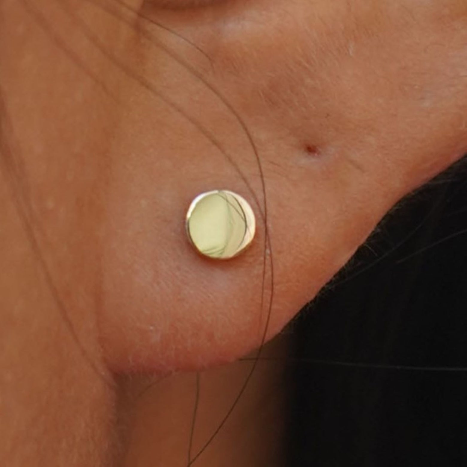 Close up view of a model's ear wearing a yellow gold Large Circle Earring