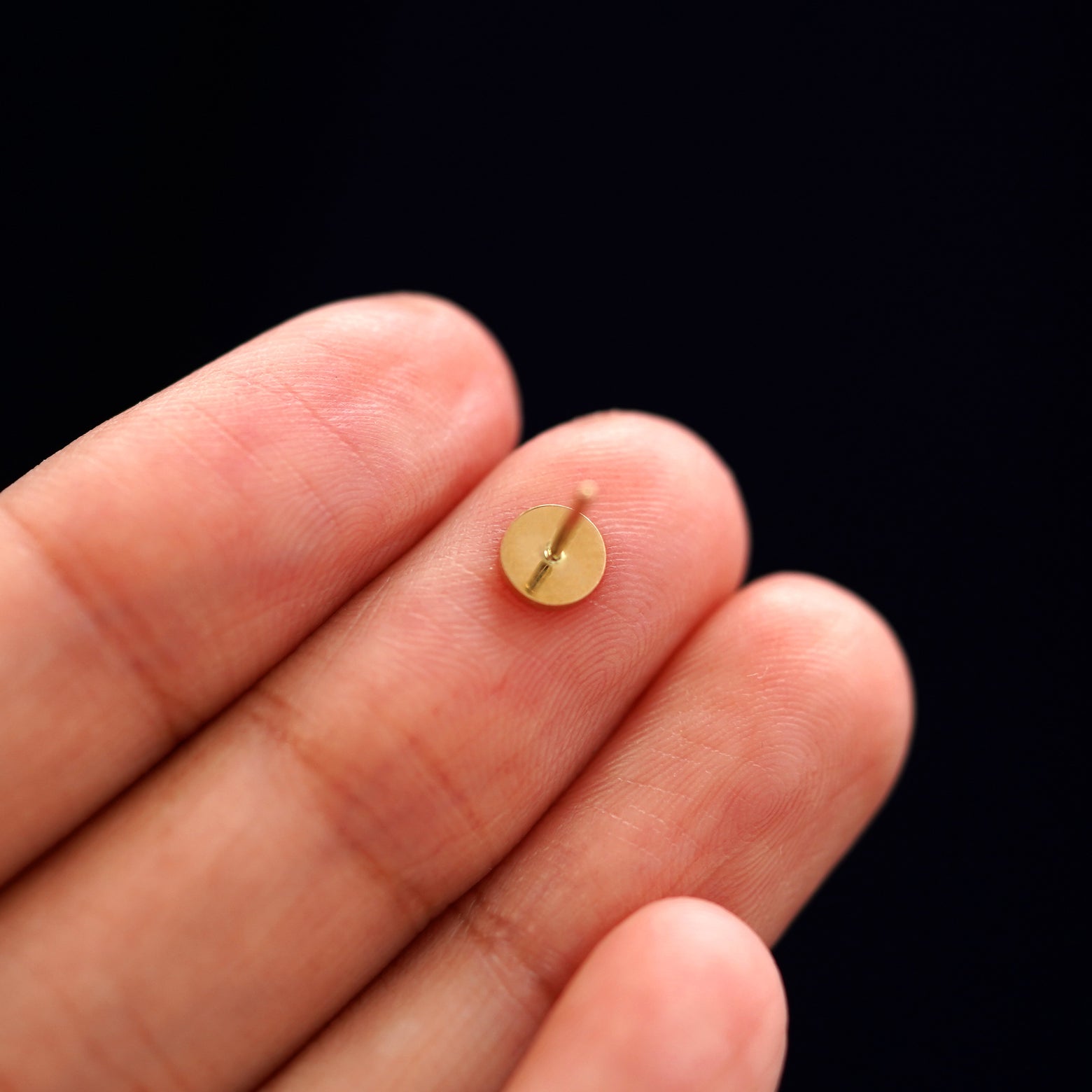 A yellow gold Large Circle Earring laying facedown on a model's fingers to show the underside view