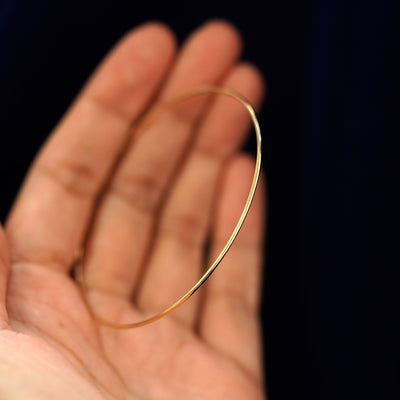 A 14k gold Large Endless Hoop Earring held in between a model's fingers to show the hoops thickness