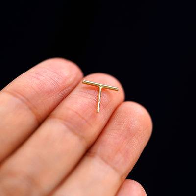 A yellow gold Large Line Earring laying facedown on a model's fingers to show the underside view