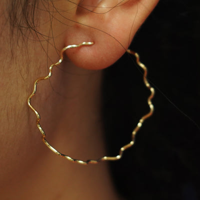 Close up view of a model's ear wearing a yellow gold Large Wave Hoop