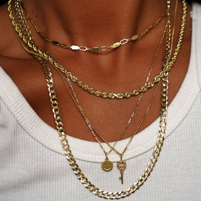 A model wearing a Tanlah Chain, Thick Rope, Mini Miami with Key Charm, Figaro with Smiley Face Charm, and a Curb Chain