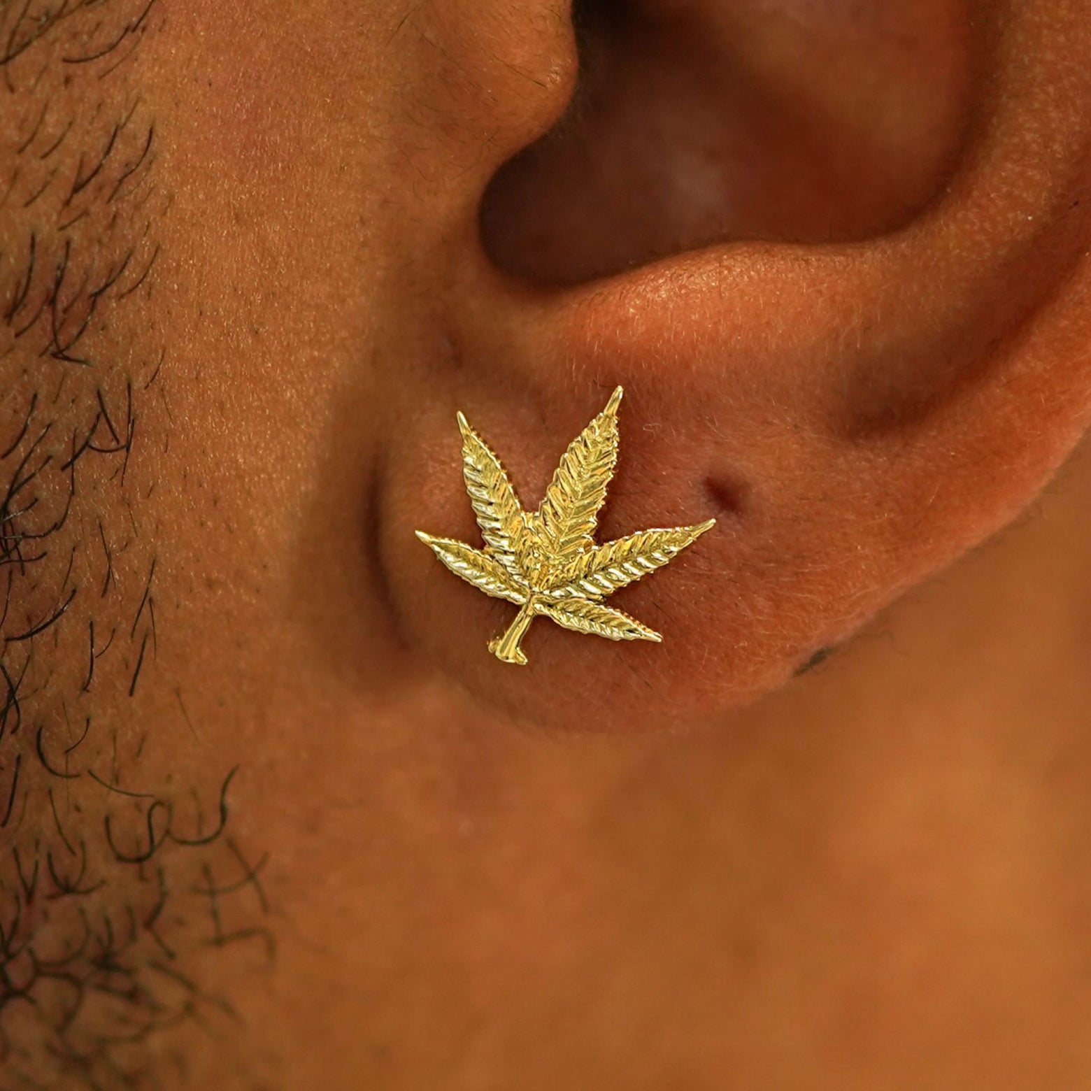 Close up view of a model's ear wearing a 14k gold Cannabis Stud Earring