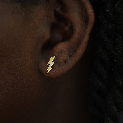 A model's ear wearing a 14k yellow gold Lightning Bolt Earring