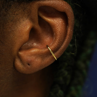 A model's ear wearing a solid gold Line Cuff