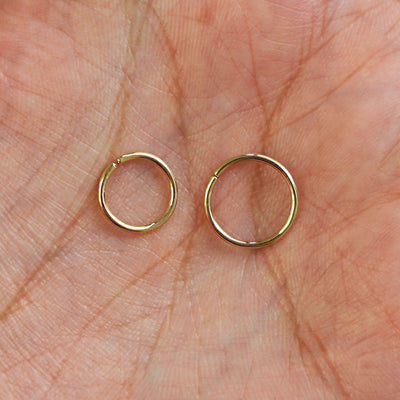 A model's palm holding two versions of the pierced Line Septum showing the 8mm and 10mm sizes