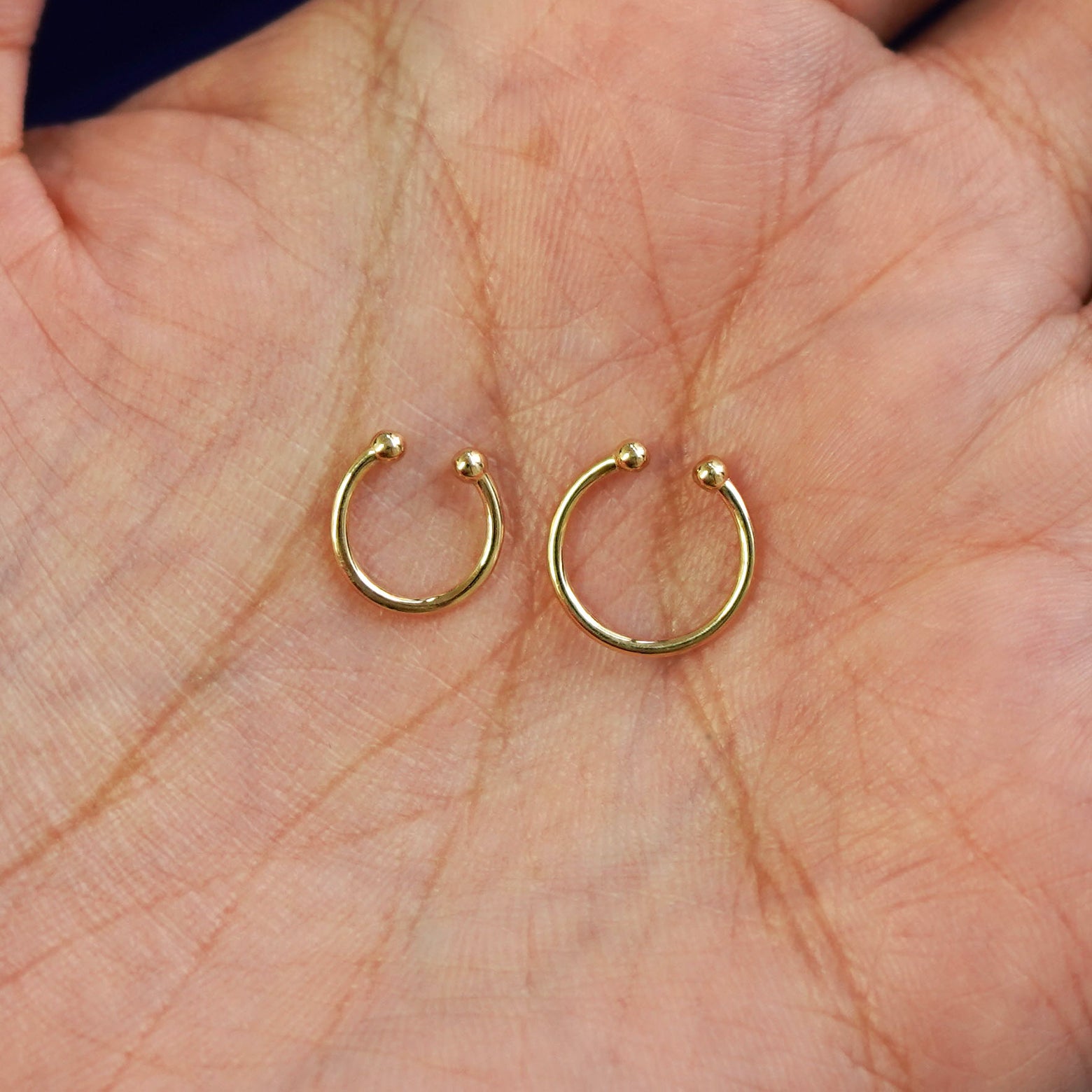 A model's palm holding two versions of the non-pierced Line Septum showing the 8mm and 10mm sizes