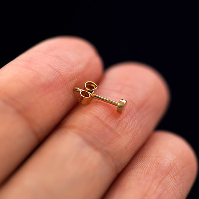 A 14k gold Mini Circle Earring sitting sideways on a model's fingertips to show detail