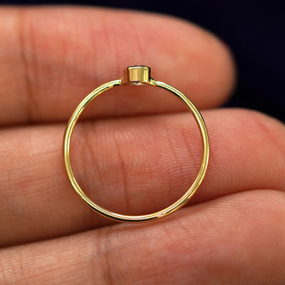 A yellow gold Aquamarine Ring in a model's hand showing the thickness of the band