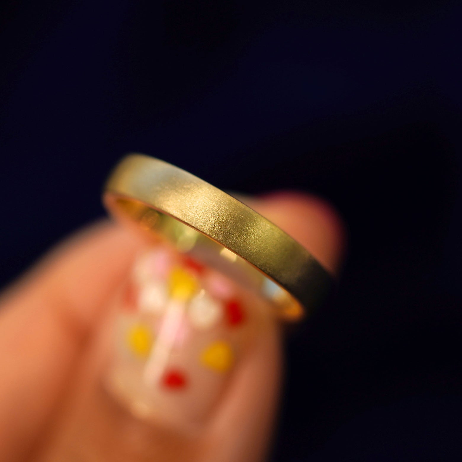 A model holding a 14k gold Mix Matte Band tilted to show the side of the ring