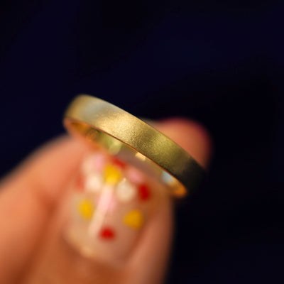 A model holding a 14k gold Mix Matte Band tilted to show the side of the ring