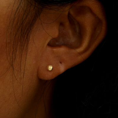 A model's ear wearing a solid yellow gold Medium Ball Earring