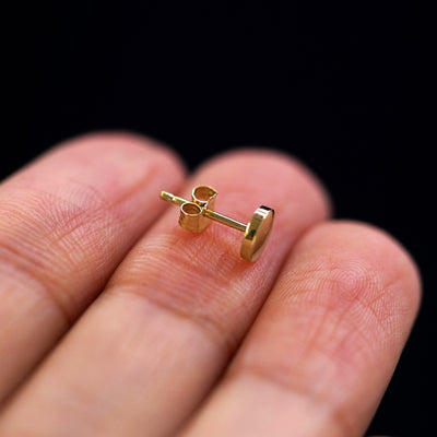 A 14k gold Medium Circle Earring sitting sideways on a model's fingertips to show detail