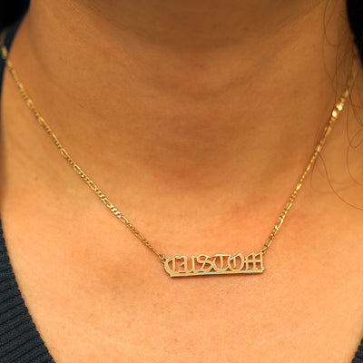 A model's neck wearing a Medium Custom Nameplate necklace that reads the word Custom