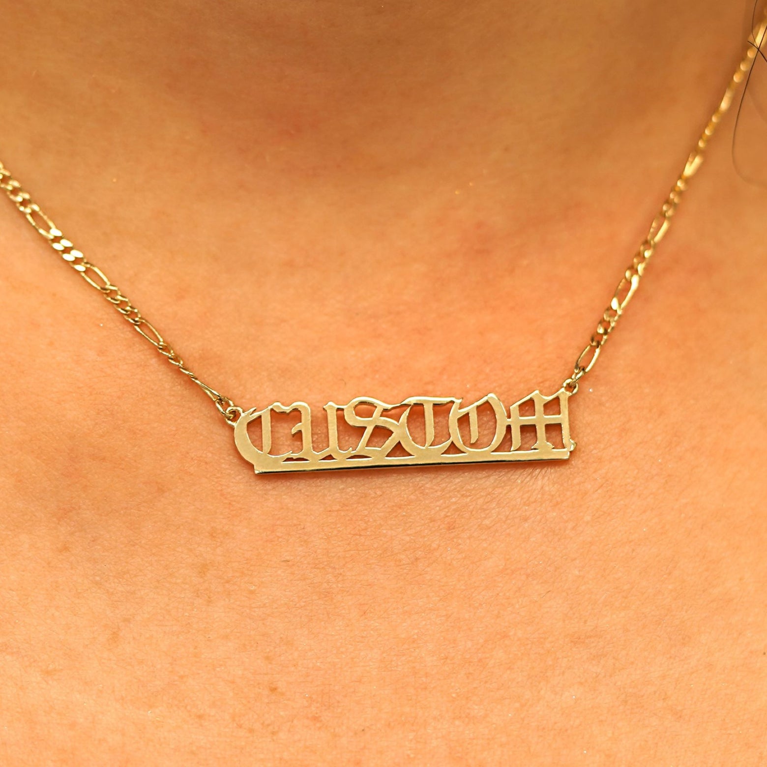 Close up view of a model's neck wearing a Medium Custom Nameplate necklace that reads the word Custom