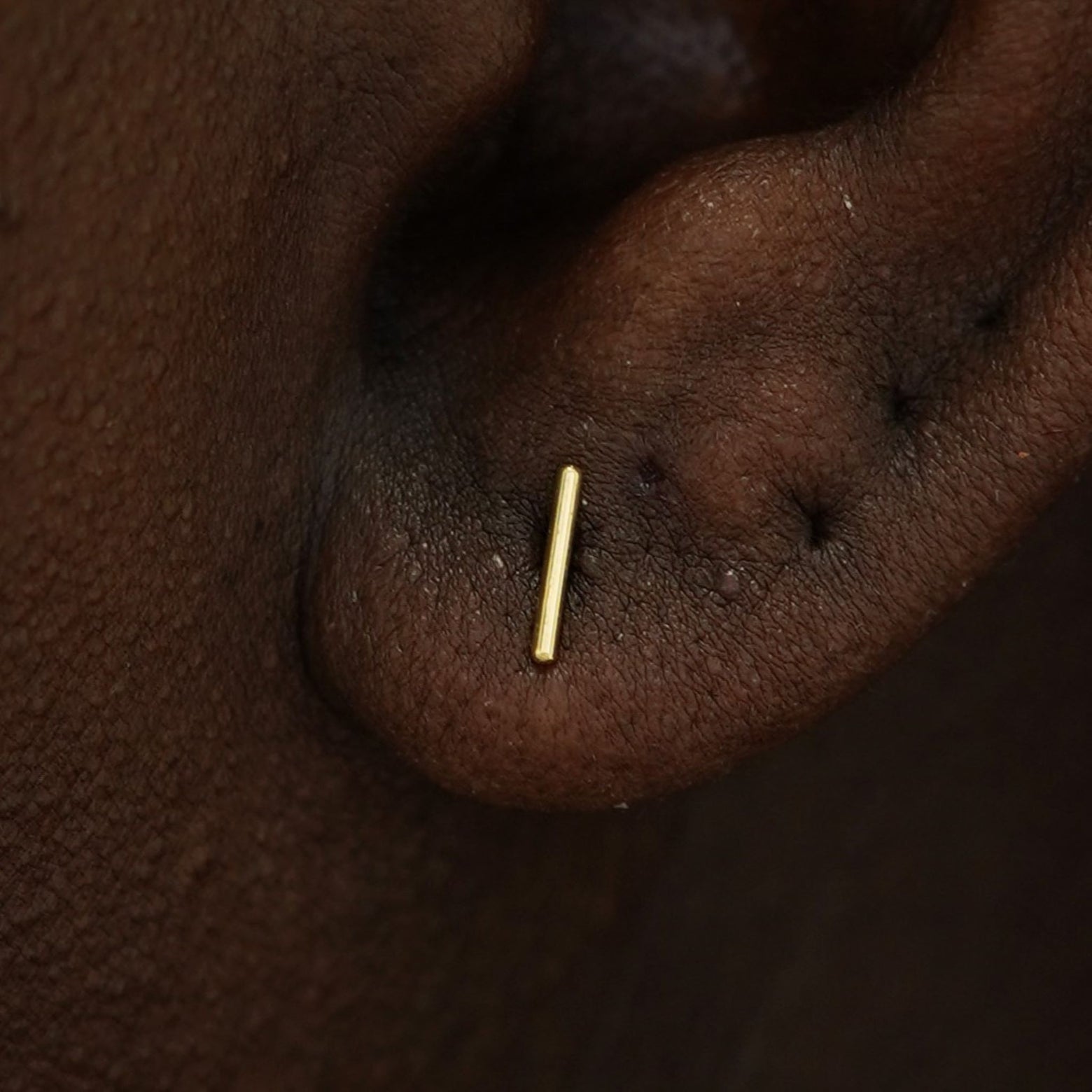 Close up view of a model's ear wearing a 14k gold Medium Line Earring