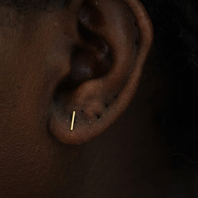 A model's ear wearing a 14k yellow gold Medium Line Earring