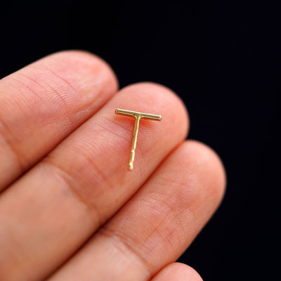 A yellow gold Medium Line Earring laying facedown on a model's fingers to show the underside view