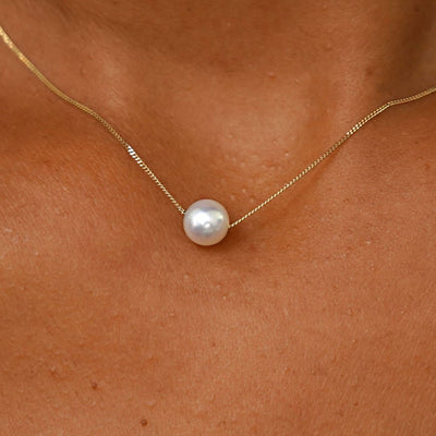Close up view of a model's neck wearing a yellow gold Pearl Slide Necklace with a 6mm pearl
