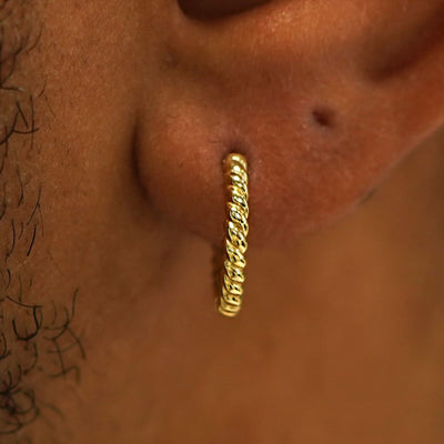 Close up view of a model's ear wearing a 14k gold Medium Rope Huggie Hoop Earring