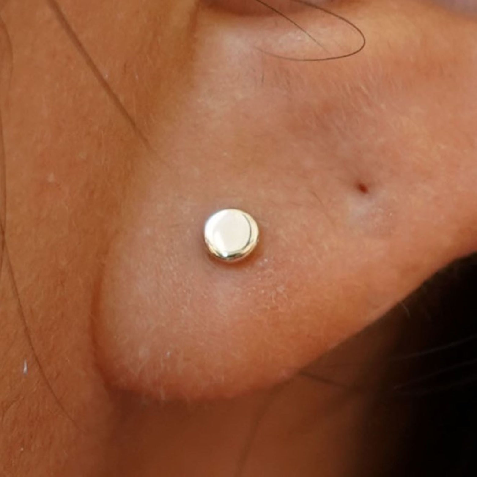 Close up view of a model's ear wearing a yellow gold Medium Circle Earring