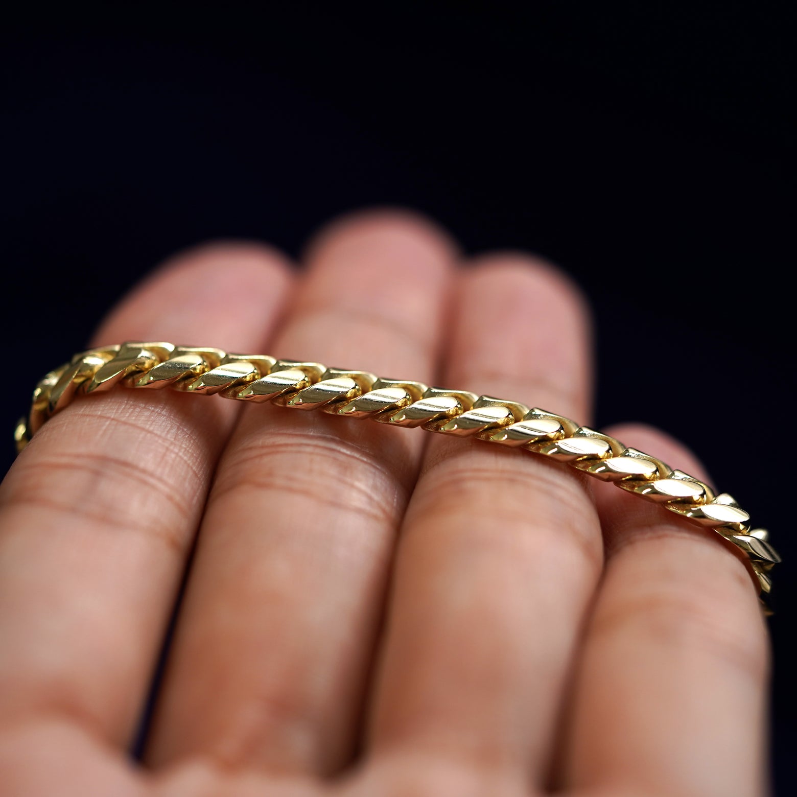 A yellow gold Miami Cuban Chain resting on a model's fingers