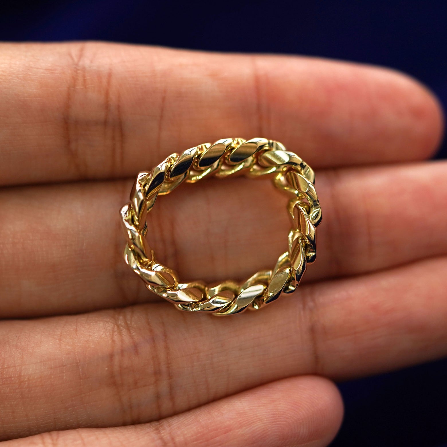 A yellow gold Miami Chain Ring in a model's hand showing the thickness of the chain