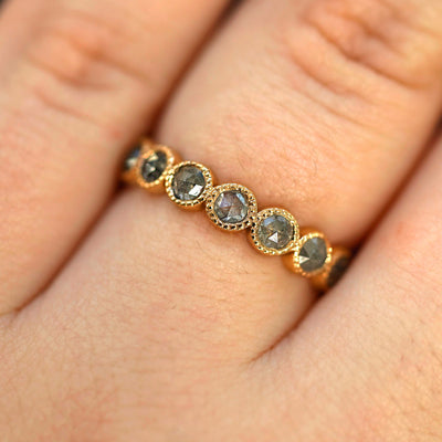 Close up view of a model's hand wearing a 14k yellow gold Milgrain Diamond Band