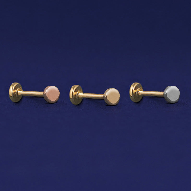 Three versions of the Mini Circle Flatback Piercing shown in options of rose, yellow, and white gold