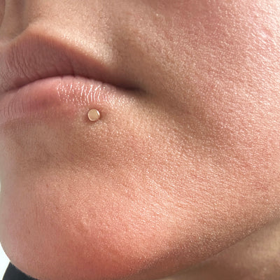 Close up view of a model's face wearing a Mini Circle Flatback in a side labret piercing