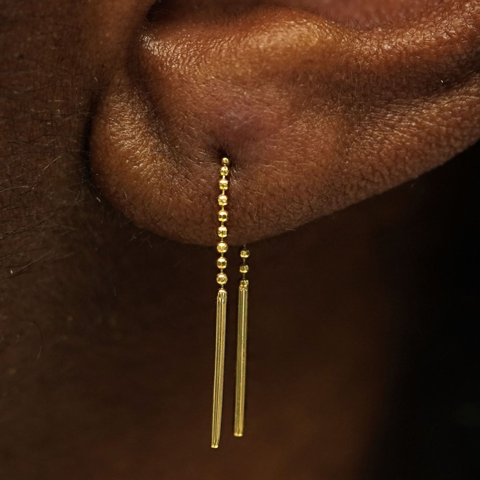 Close up view of a model's ear wearing a solid 14k yellow gold Mini Threader