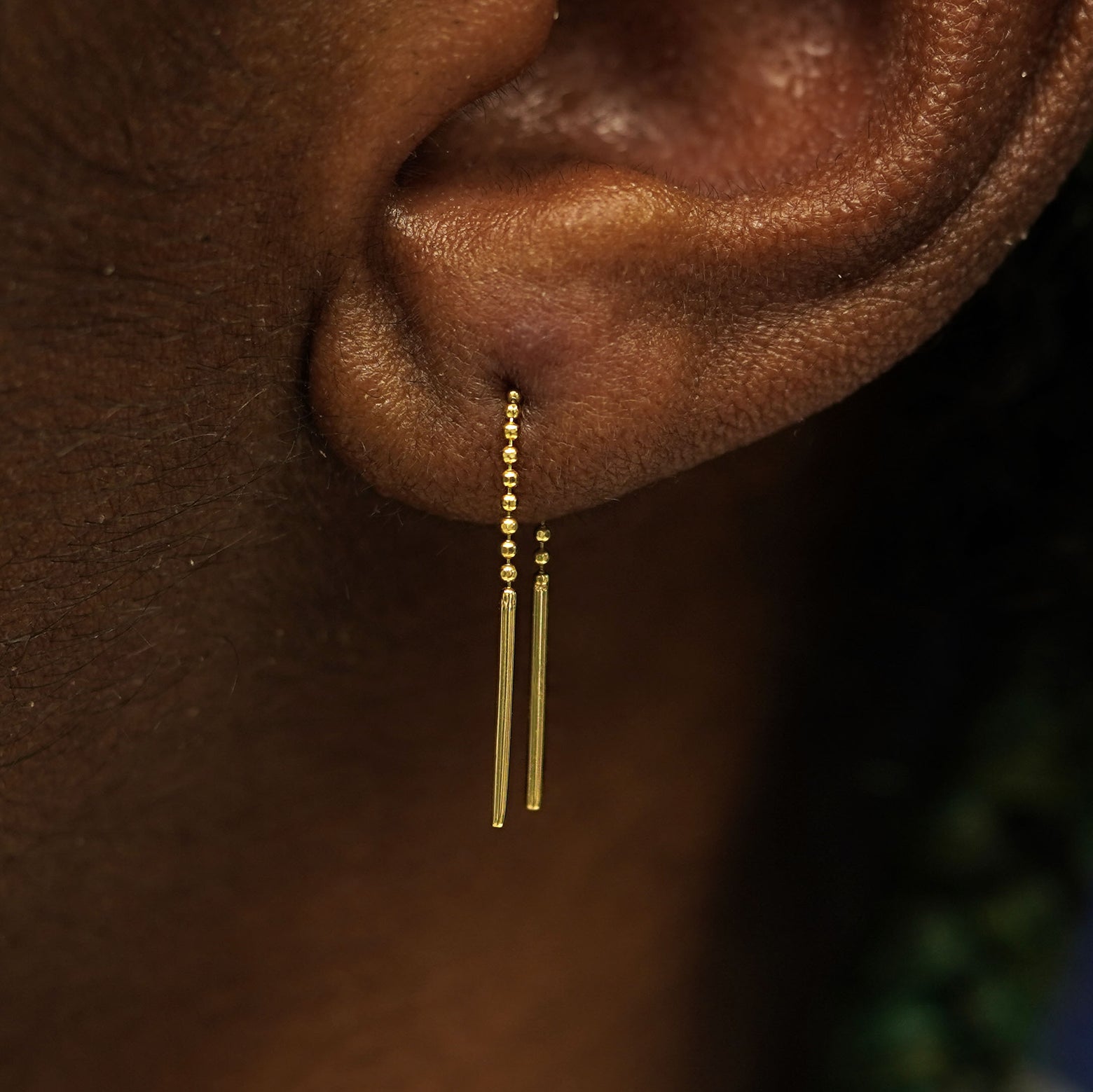 A model's ear wearing a solid yellow gold Mini Threader